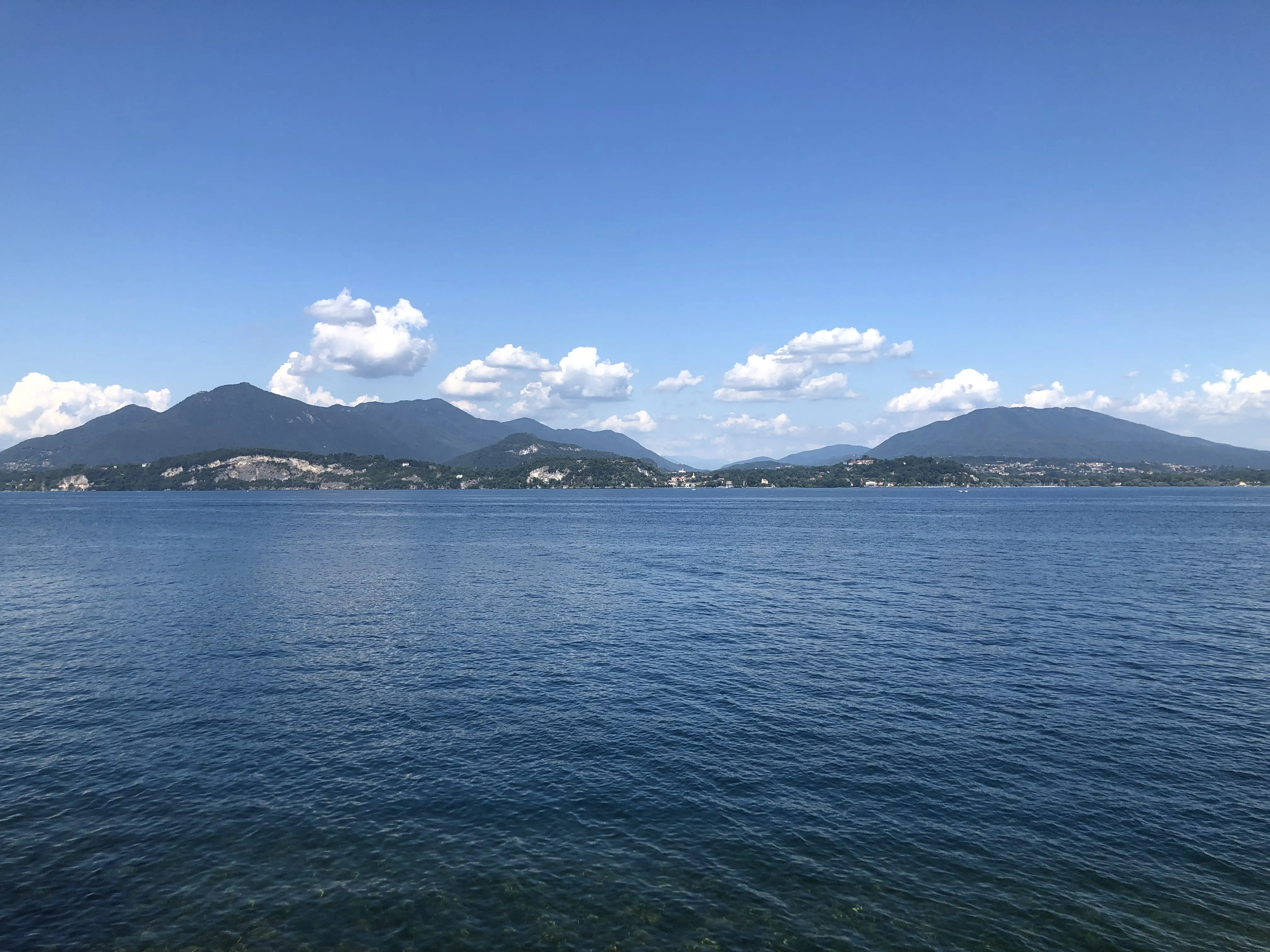 A calm blue lake under a clear sky, wooded hills on the far shore